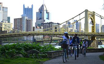 people on bikes near Pittsburgh bridge