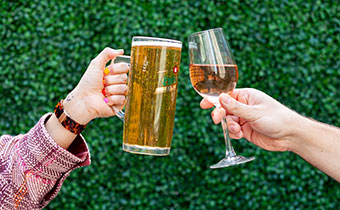 People cheersing a glass of wine and a beer