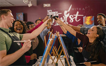 people cheersing with wine at a paint n sip class
