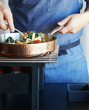 Chef in Blue Apron Cooking for a class in a copper pan